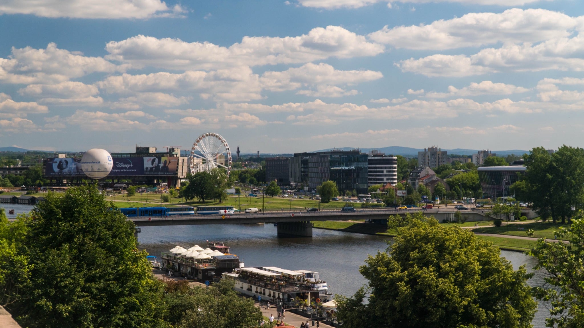 A Ferris wheel and tethered observation balloon on the far bank of the Vistula River