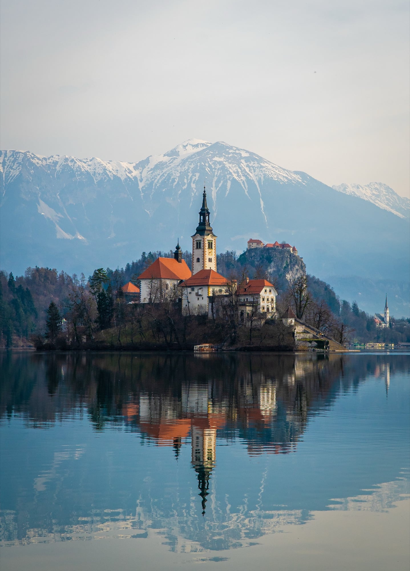 The island church of Lake Bled mirrored in the still water below the Julian Alps