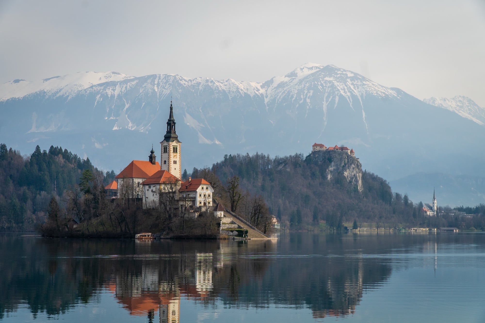 The island church on Lake Bled with the clifftop castle and snow-dusted mountains behind
