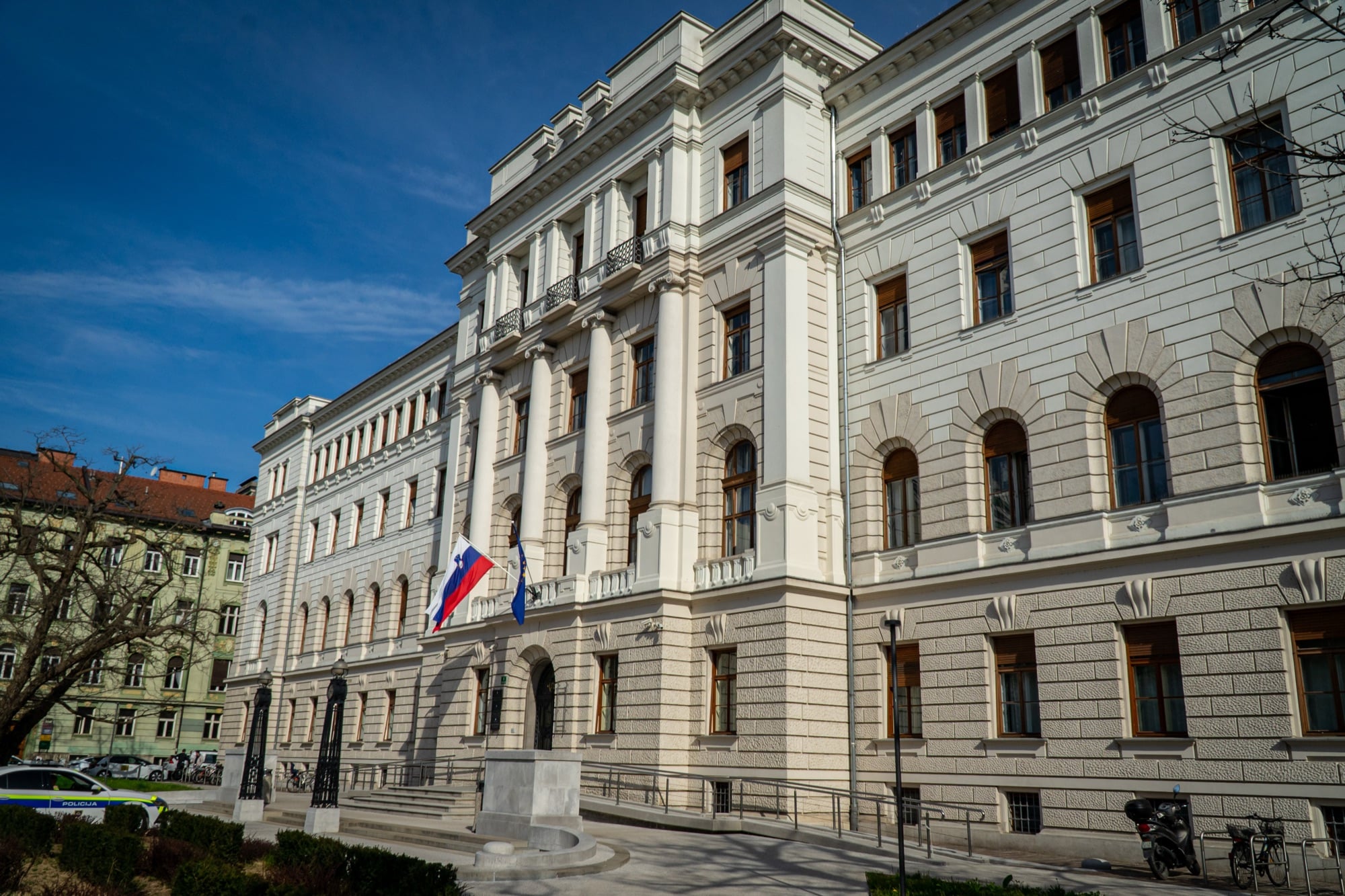 A grand neoclassical civic building flying the Slovenian flag, Ljubljana