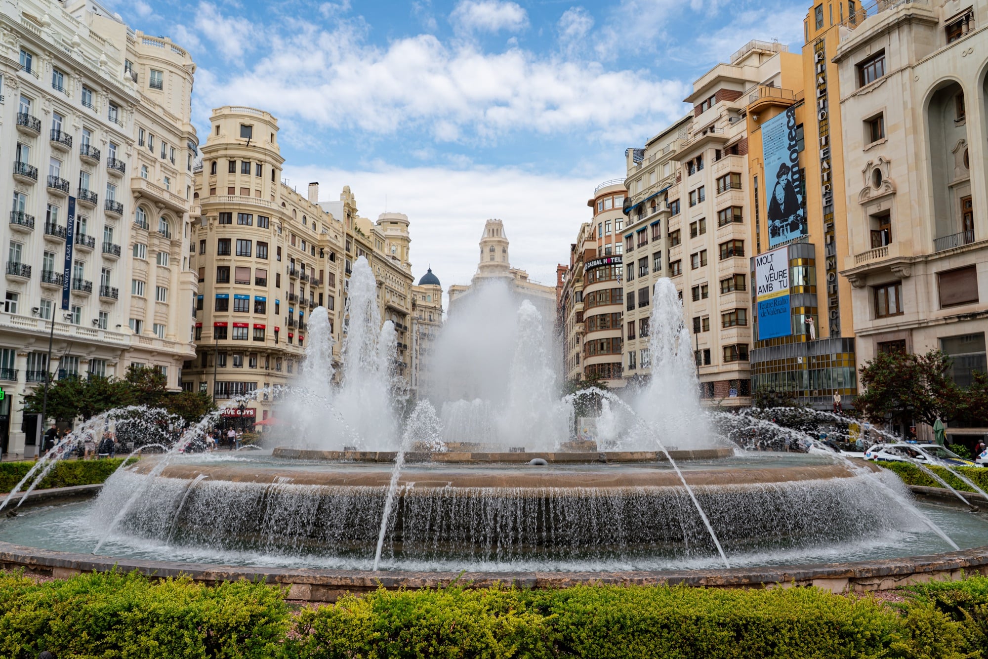 The great fountain of the Plaza del Ayuntamiento throwing up its jets before a ring of grand apartment buildings