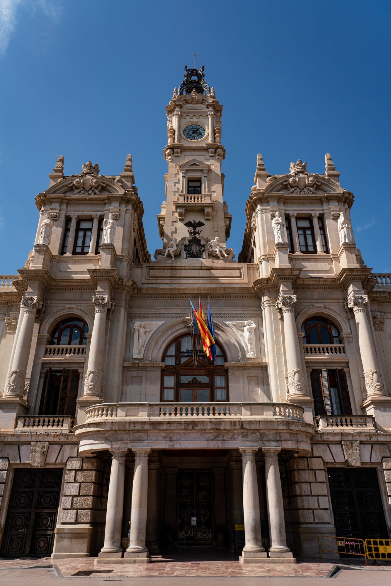 Valencia City Hall seen straight on, its columned portico and flag-draped balcony beneath the clock tower
