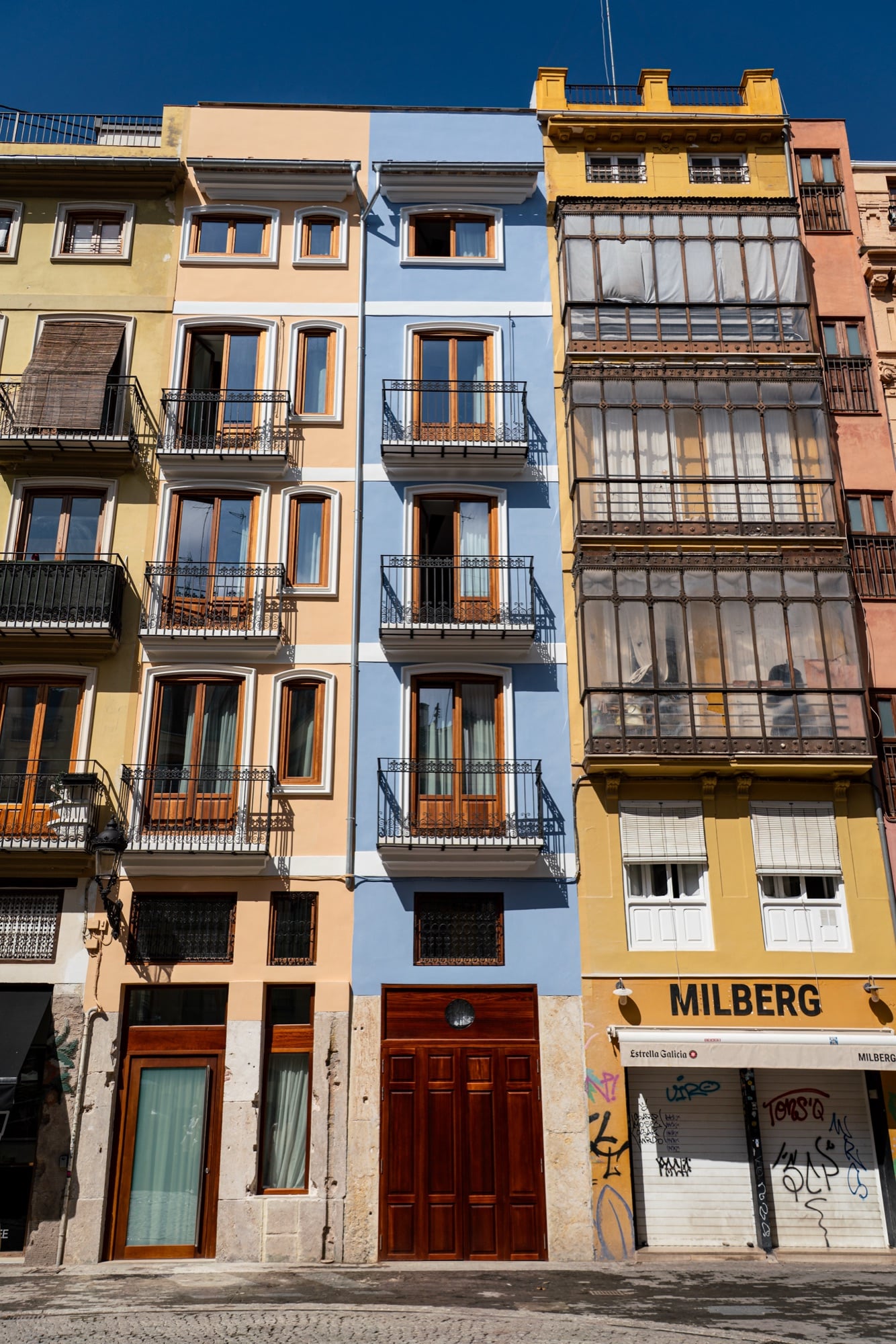 Narrow townhouses painted ochre, blue and cream with glazed balconies and wooden shutters in the old town