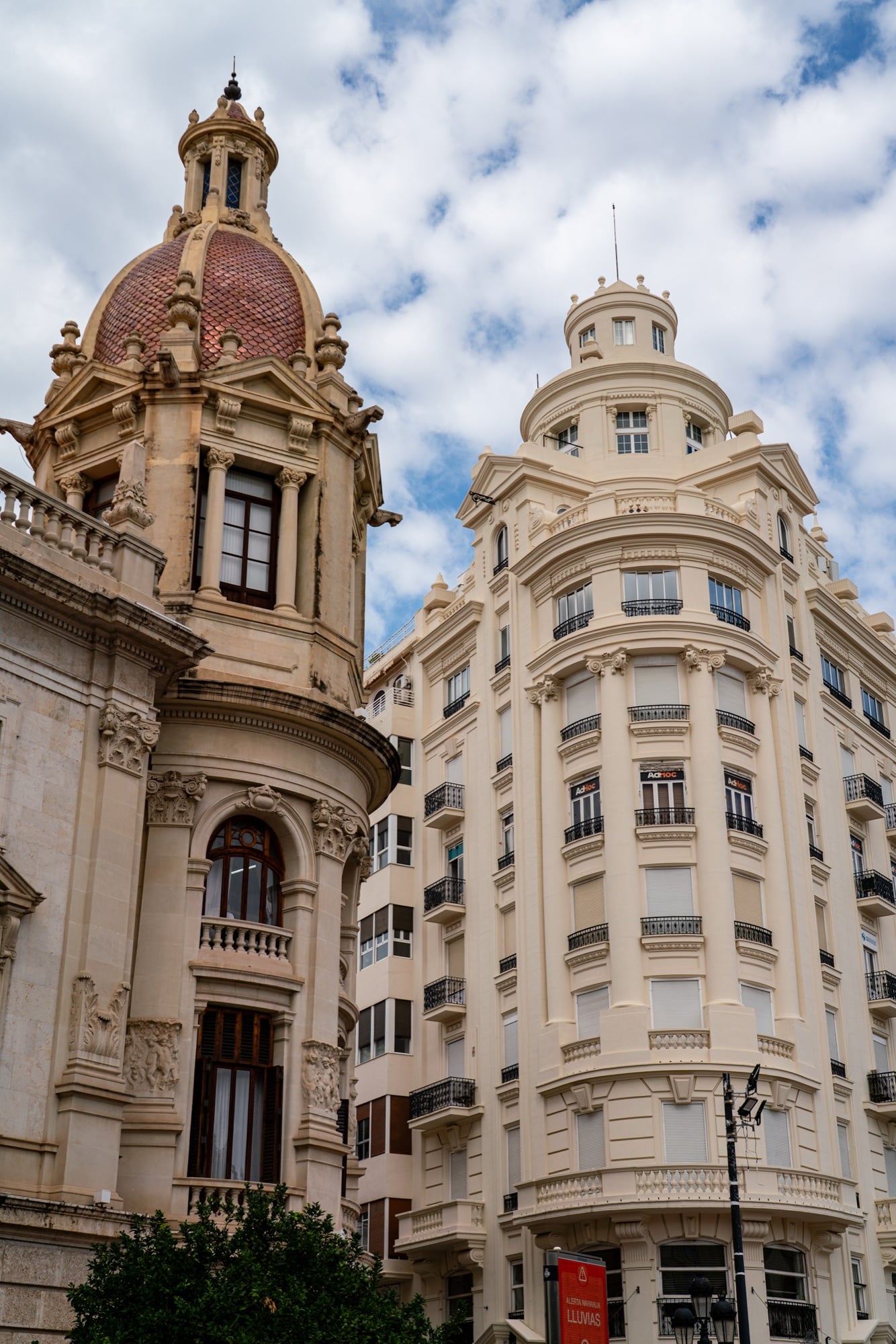 A red-tiled cupola on the corner of Valencia City Hall beside a cream apartment block with stacked balconies