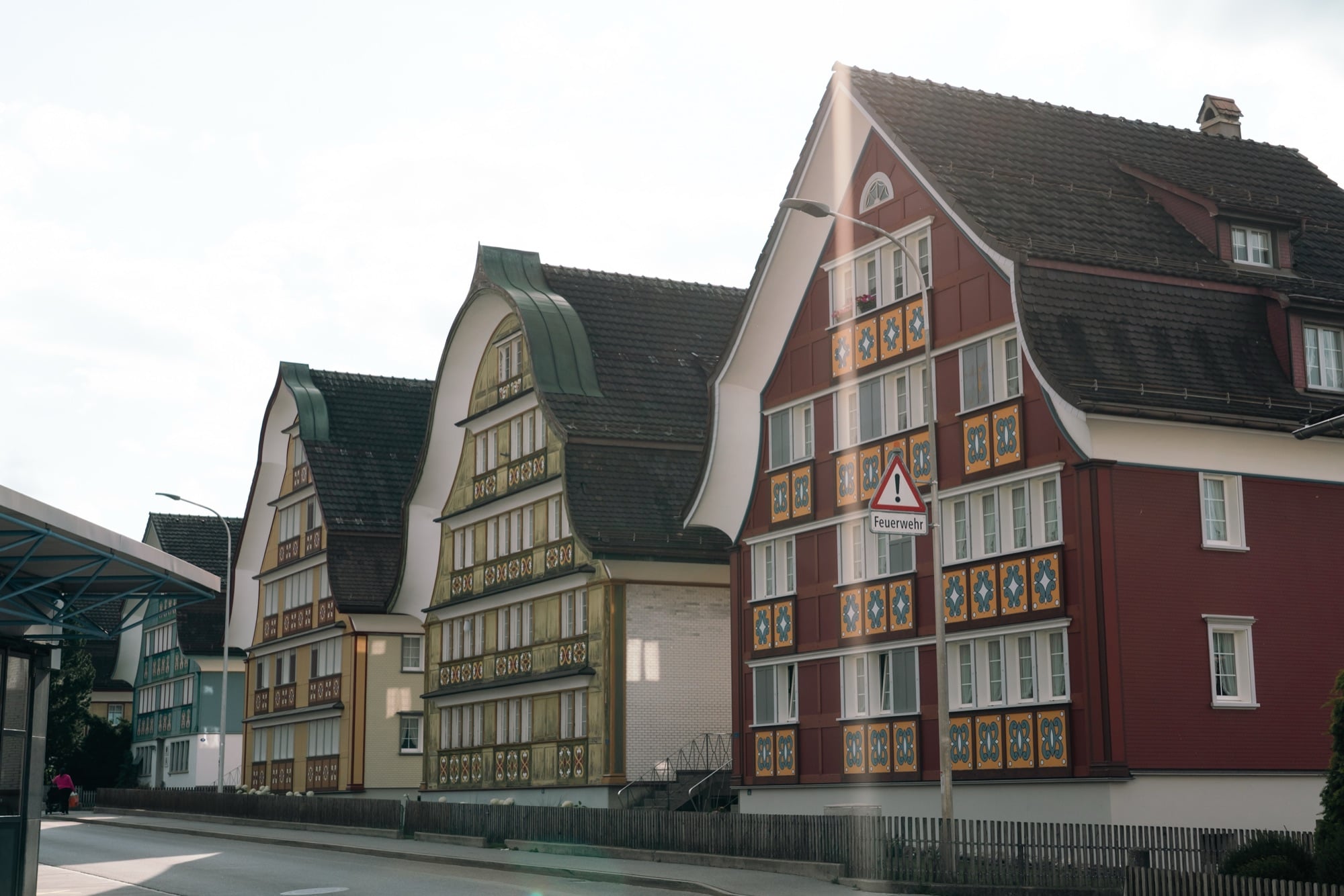A row of Appenzell's curved-gable houses in yellow, olive and deep red, their facades ornately painted