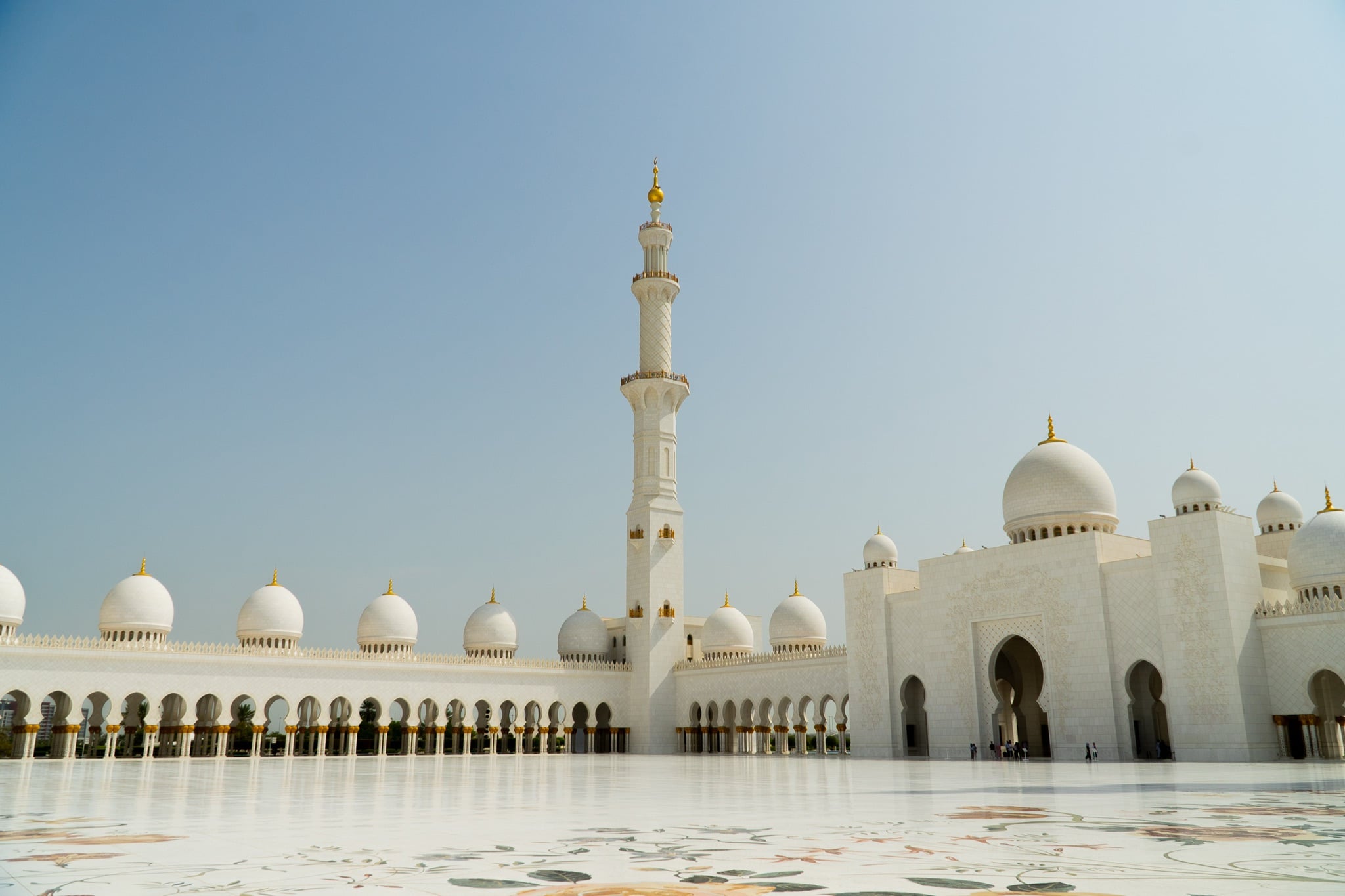 The mosque's white facade reflected in the wet marble