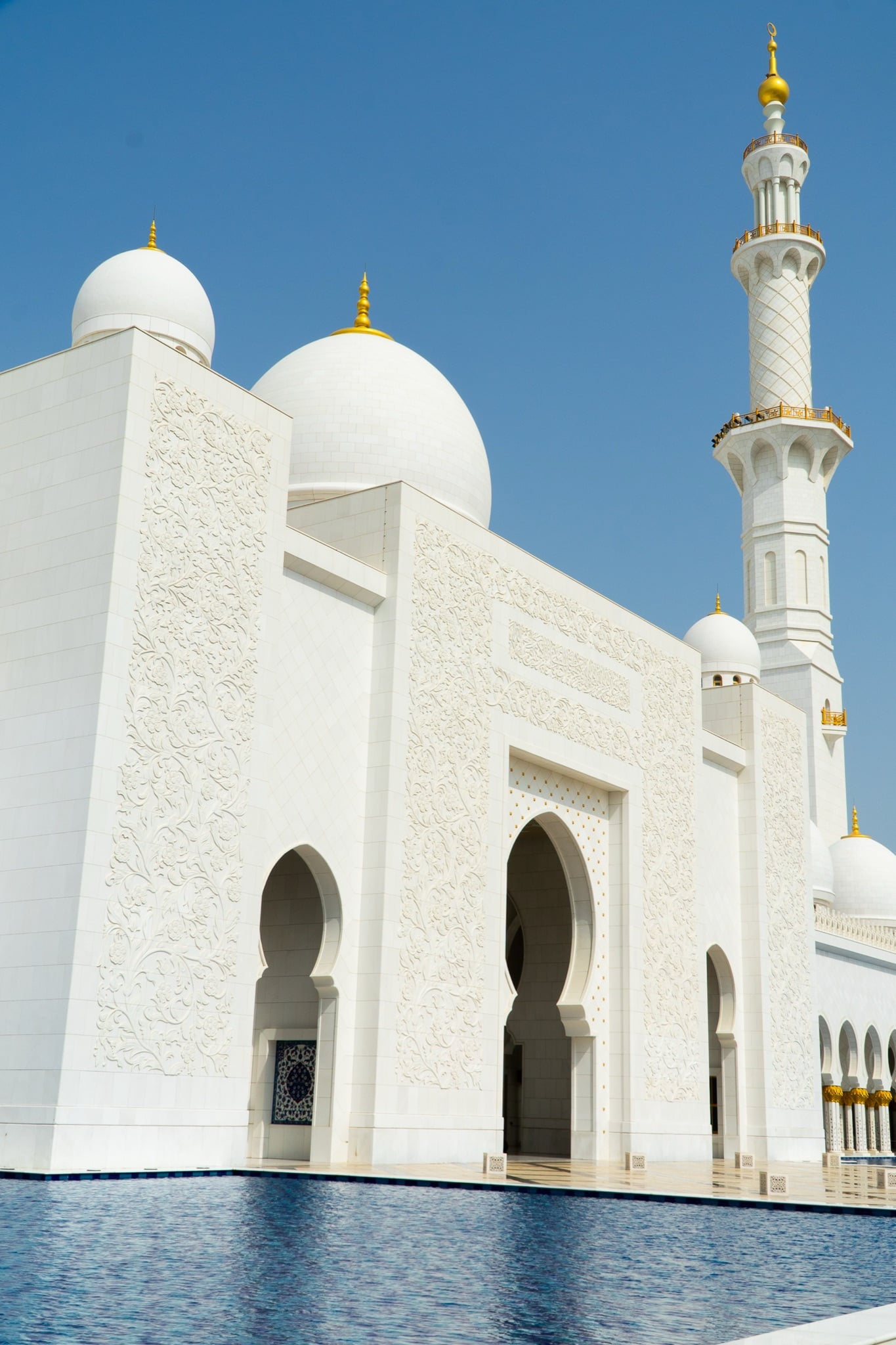A white dome and minaret of the Grand Mosque against a clear sky